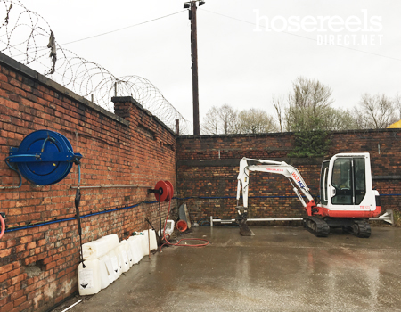 Spring rewind reel mounted at a concrete mixing plant and used for jet washing vehicles