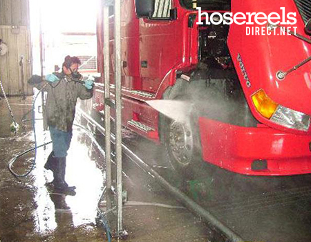 Man using a jet wash reel and lance in a wash bay