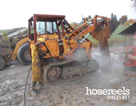 Jet washing a muddy JCB