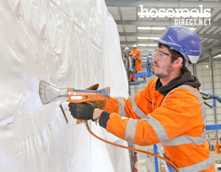 Man using a propane shrink wrap heat gun with propane hose